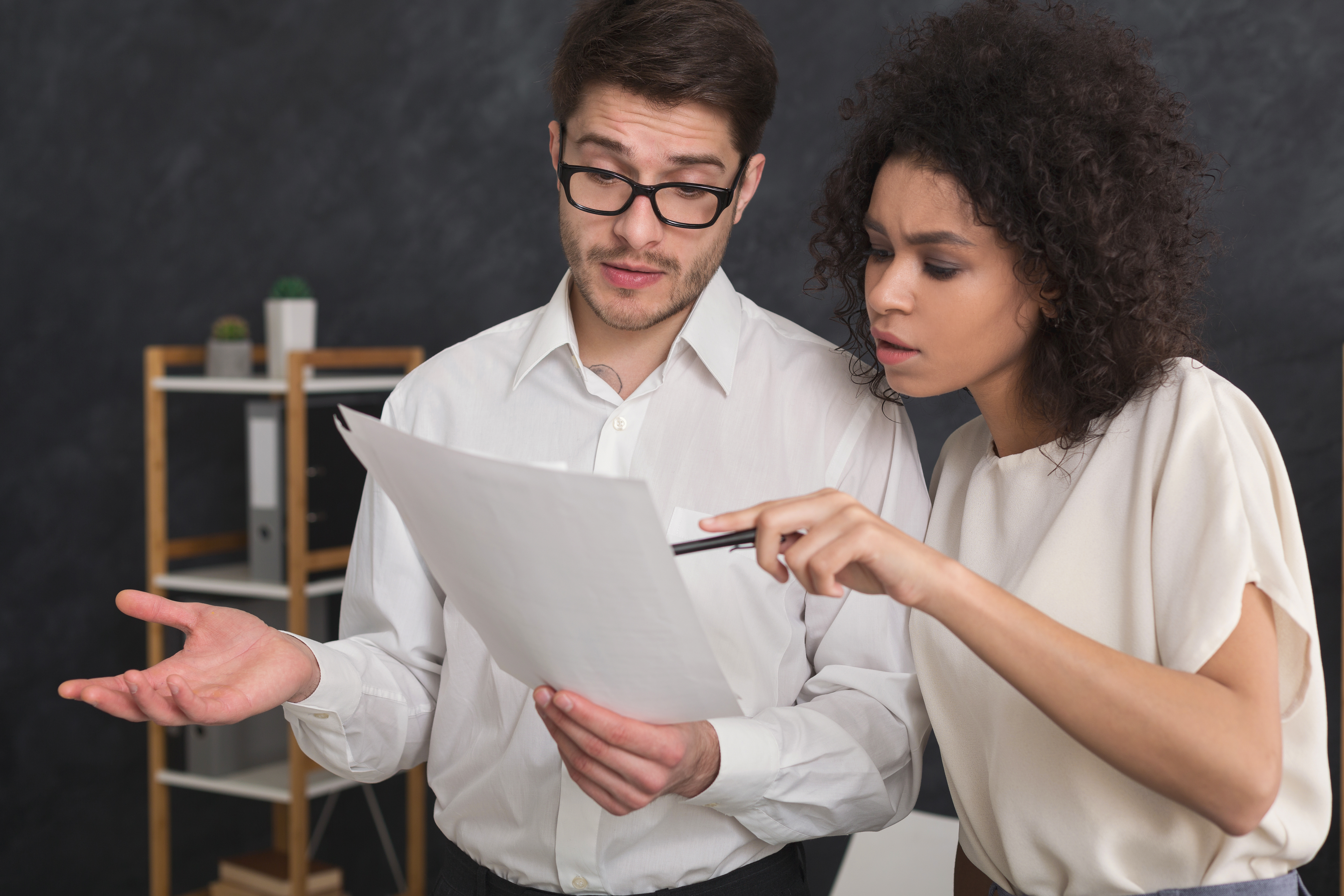 Two people reviewing a document together, looking confused