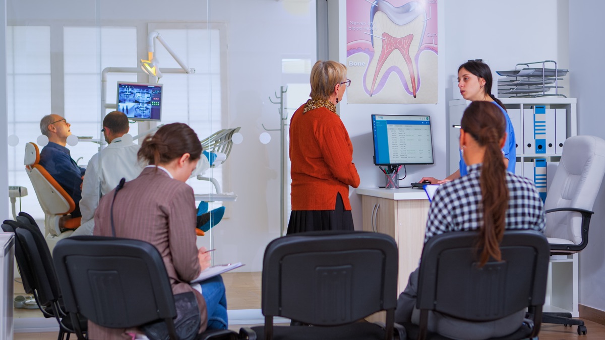 Busy dental reception with patients waiting and receptionist at the front desk